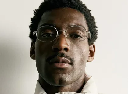 A young man in glasses and a cream puffer jacket